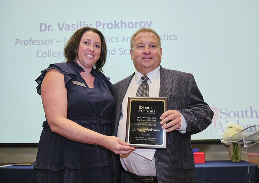 Two alumni holding an award.