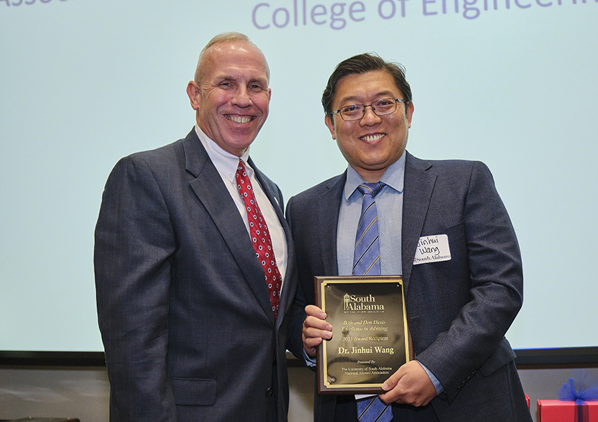 Two alumni holding an award.