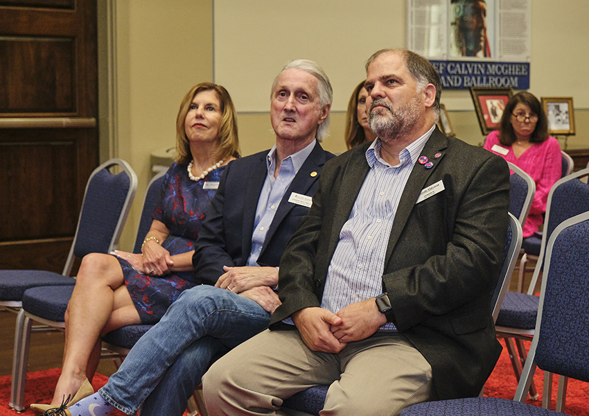 Three alumni watching a presentation.