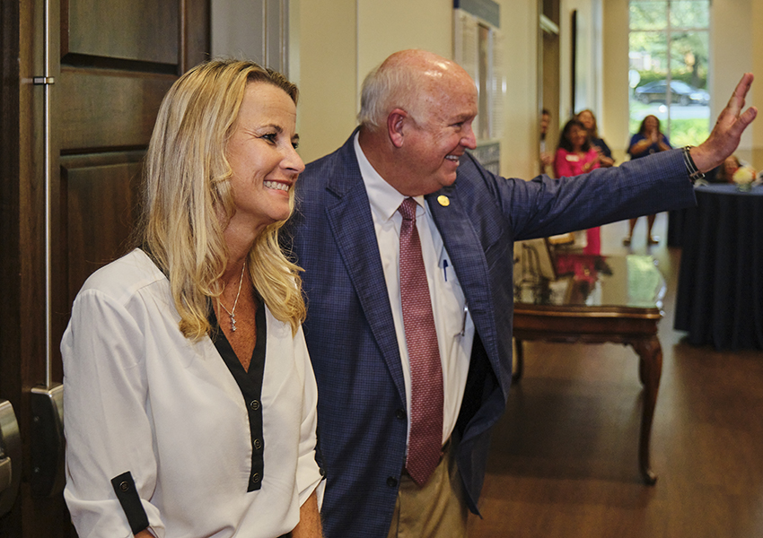 Two alumni waving at other alumni.