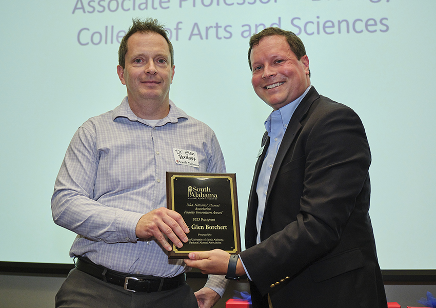 Two alumni holding an award.