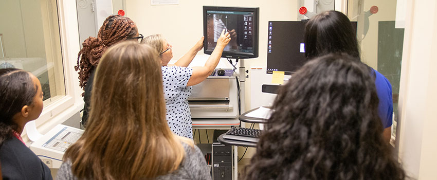 Students looking at monitor as professor teaches,