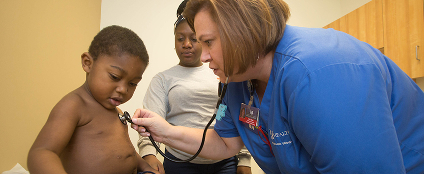 Nurse listening to chest of child with her stethoscope.