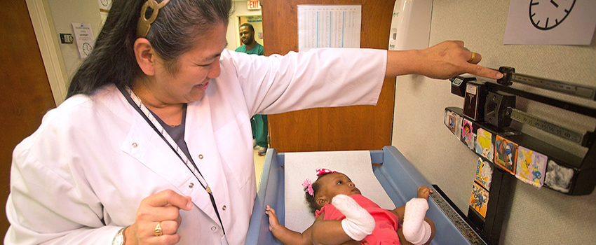 Nurse checking the weight of a baby on a scale.