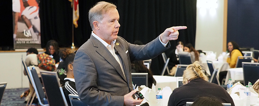 Speaker at conference talking to crowd pointing.