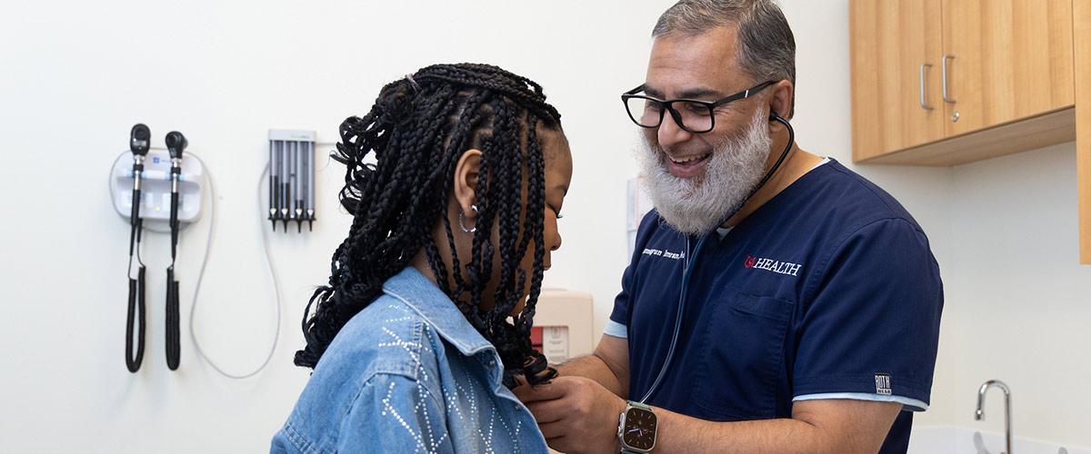 USA health worker listening to patient breathing with a stethoscope in a doctors office.