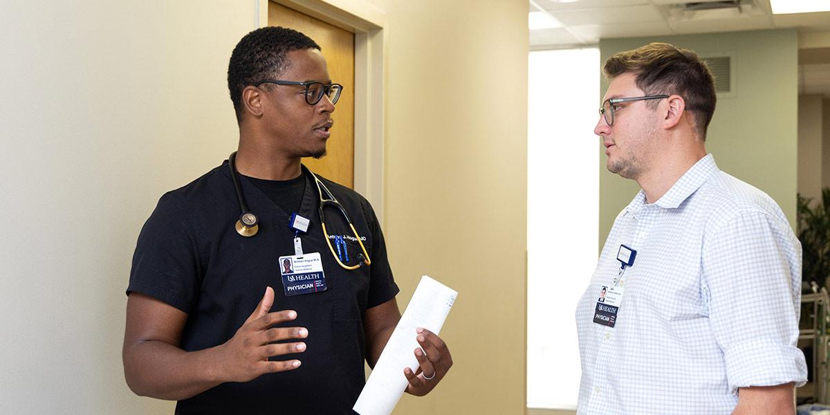 Physician and resident discusses treatment plan in clinic.