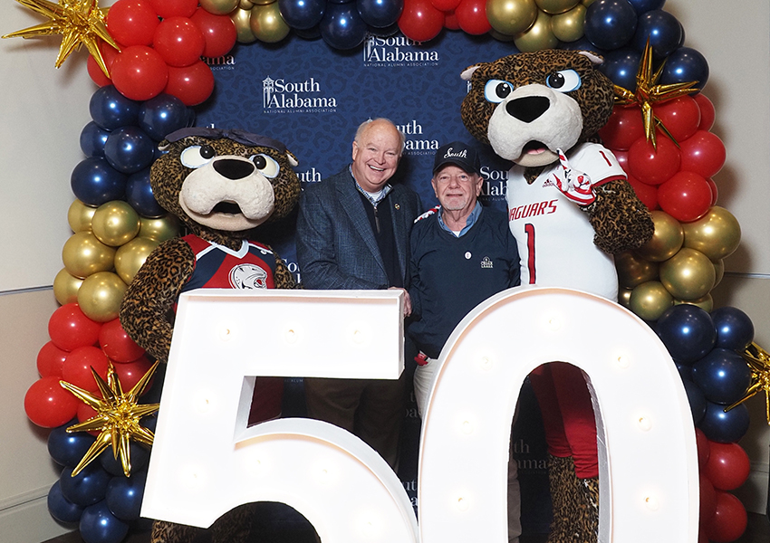 South Alabama's President Joe Bonner with South Alumni posing behind the "50" beside Ms. Paula and South Paw