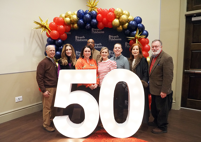 Alumni's pose behind the "50" beside Ms. Paula and South Paw