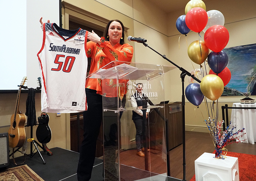 Alumni speaking at USANAA 50th Anniversary celebration while holding a number 50 South Alabama basketball jersey