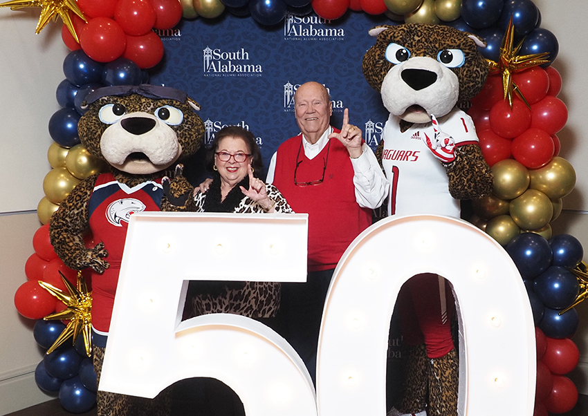 Alumni's pose behind the "50" beside Ms. Paula and South Paw