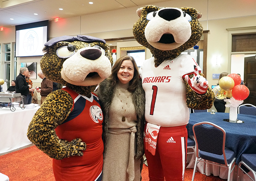 Alumni poses beside Ms. Paula and South Paw