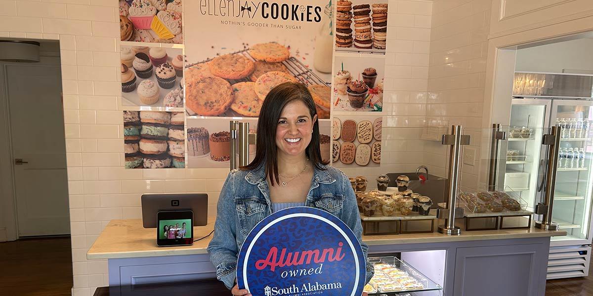 ellenJAY Bakery owner holding up Alumni owned sign