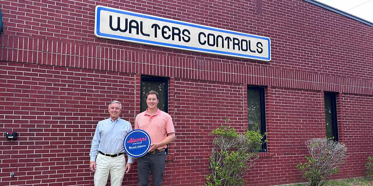 Walters Controls owners holding up Alumni owned sign