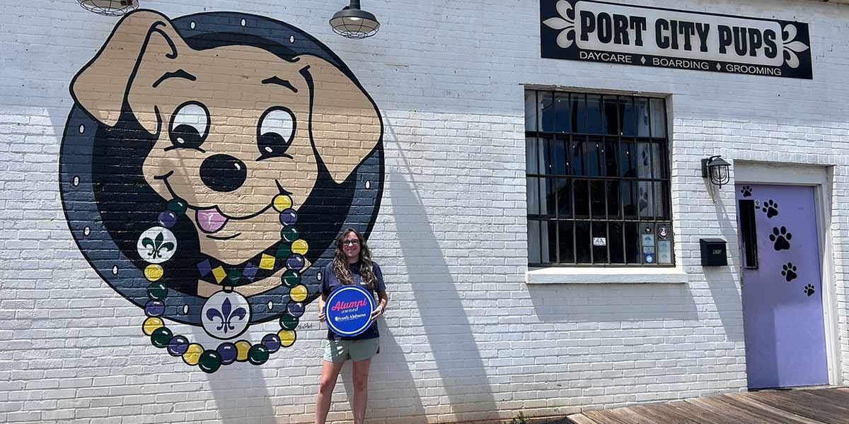 Port City Pups owner holding up Alumni owned sign