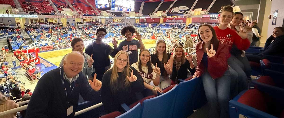 Students taking a picture with Joe Bonner the University of South Alabama President at the basketball game