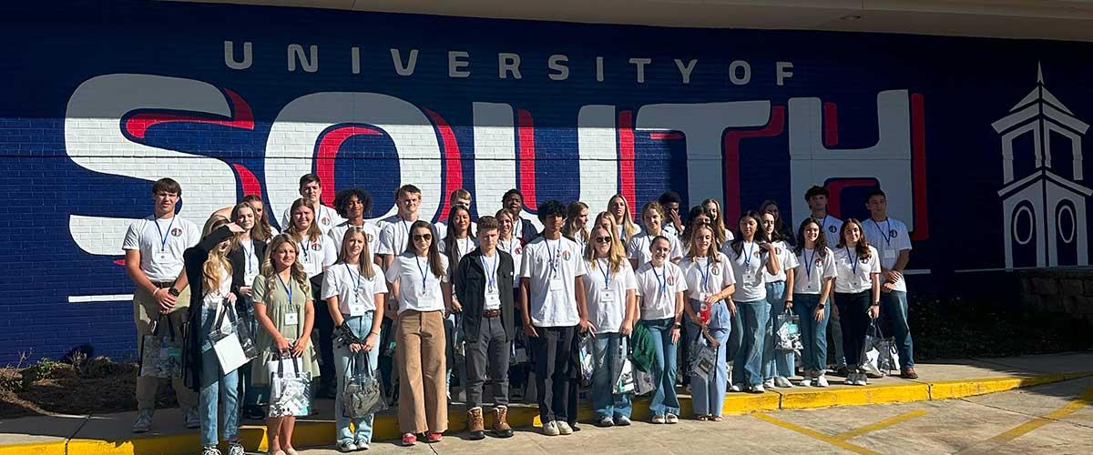 Student members taking a photo in front of the "South" mural at the student center