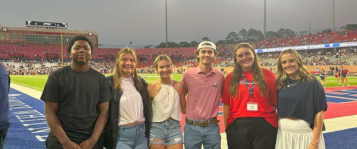 Students on the field for gameday in Hancock Whitney Stadium