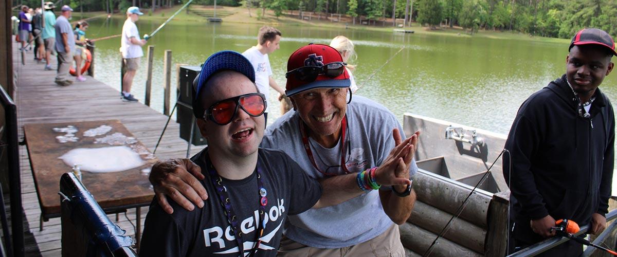 Male holding up fish with another man behind him smiling.