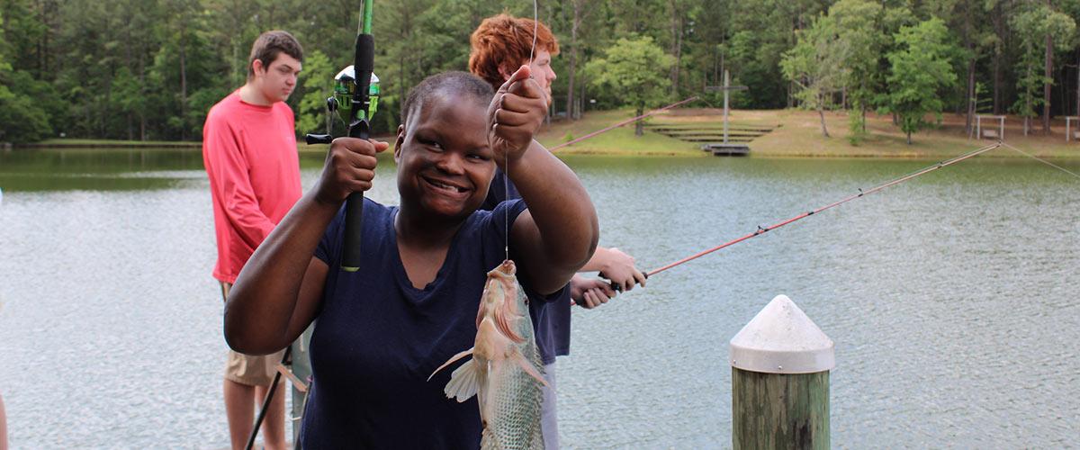 People fishing with one person holding up fish,