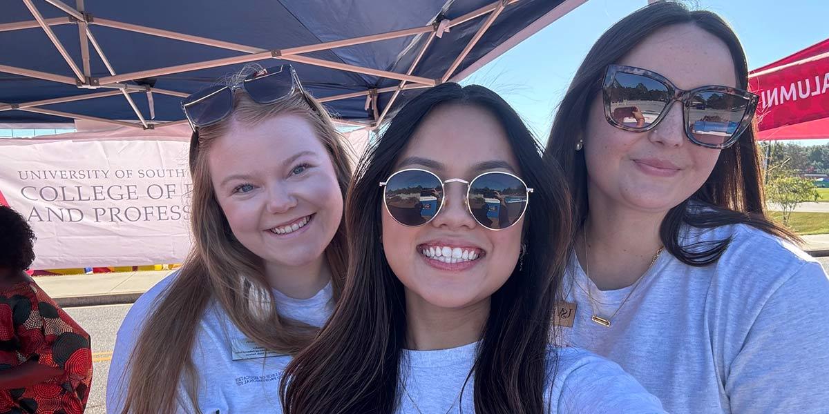 Three CEPS Ambassadors under a tailgate tent.