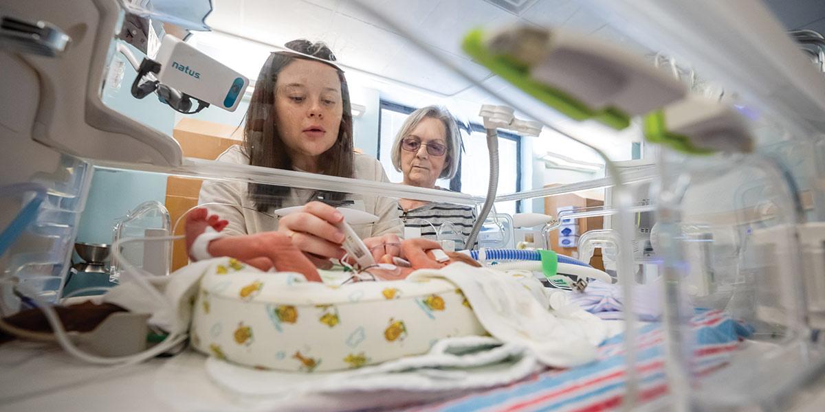 A SMALL CAMERA above each NICU bed allows parents to check in through a secure app. When families are here in person, they see what they can also view from home: a tiny body sur-rounded by care.
PARENTS QUICKLY 
LEARN the unit’s 
language: terms like 
sats (a baby’s oxygen 
level) and FiO₂ (how 
much oxygen the 
team is giving). It 
becomes part of how 
they understand each 
day’s progress.