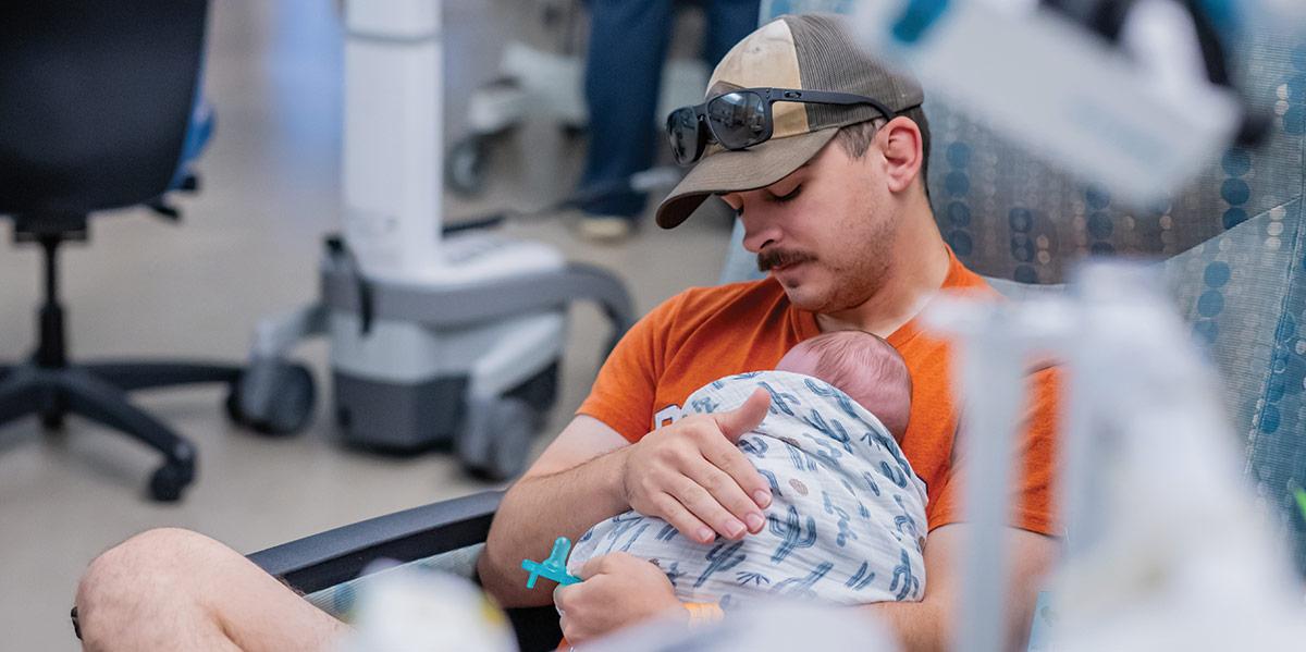 Father holding baby in the NICU.