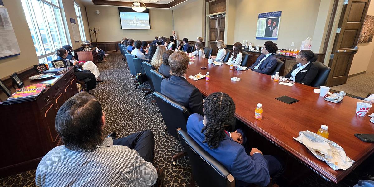 Group sitting in boardroom with screen at the front.