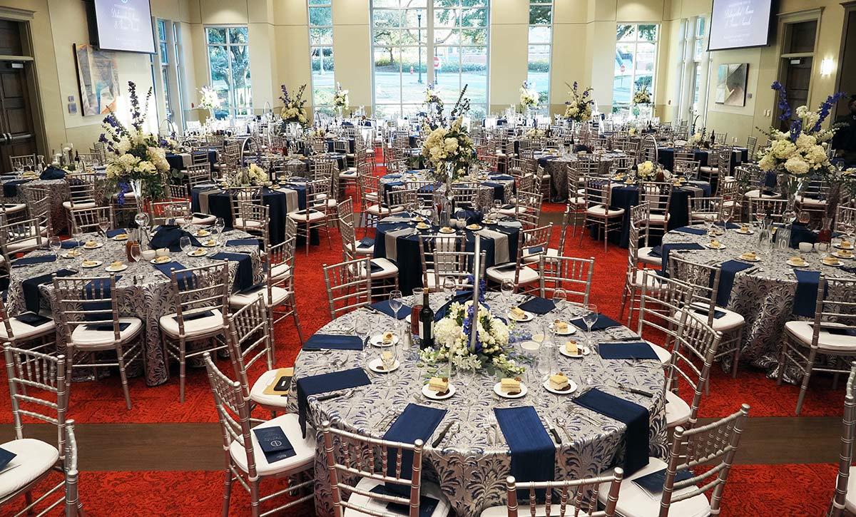 Tables and chairs with blue and silver decorations in ballroom.