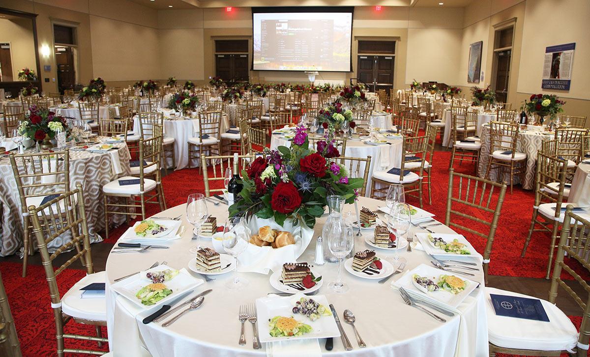 Tables and chairs set up with decor in ballroom.