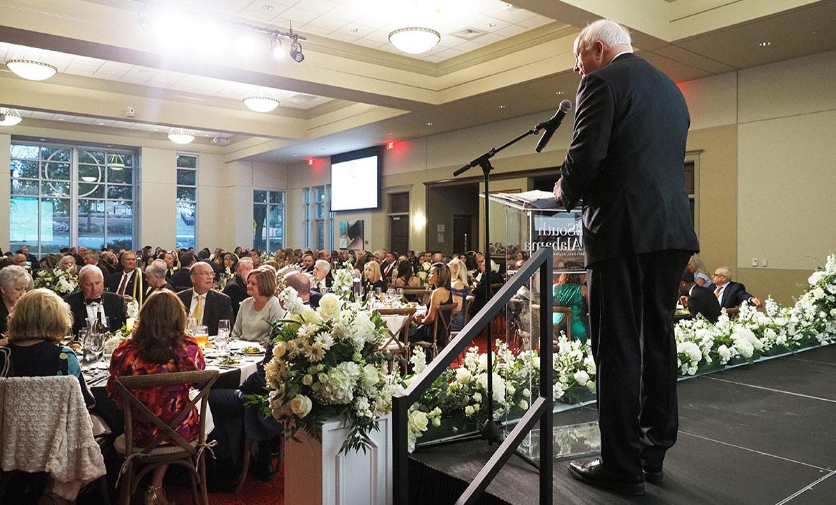 President Bonner speaking on stage in ballroom.