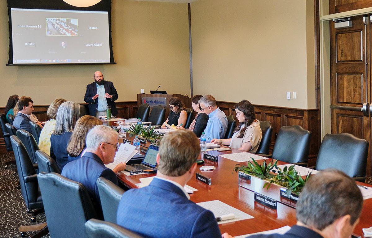 Person speaking at head of boardroom table.