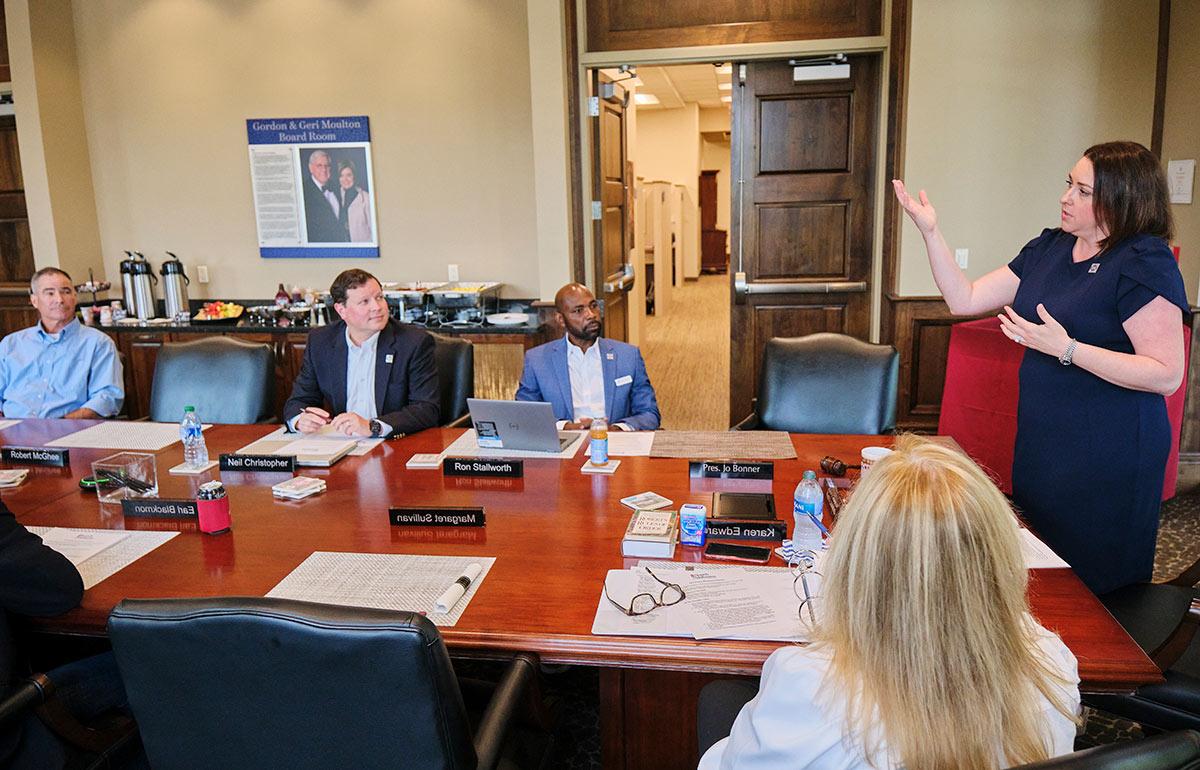 Alumni association president speaking in boardroom to group.