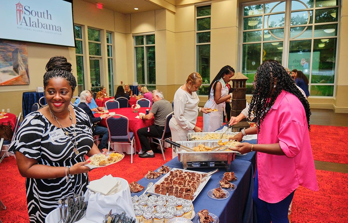 People fixing plates of food at the National Alumni Association meeting.