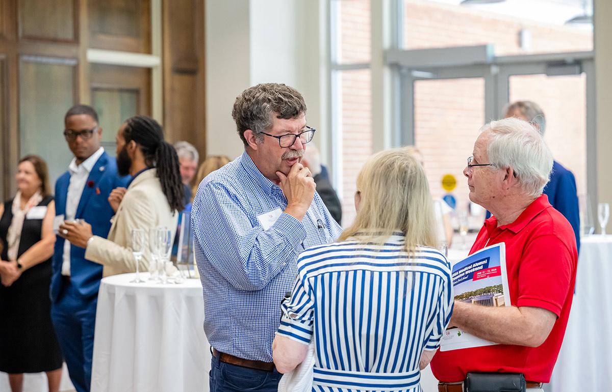 Medical Alumni Association meeting with three people talking.