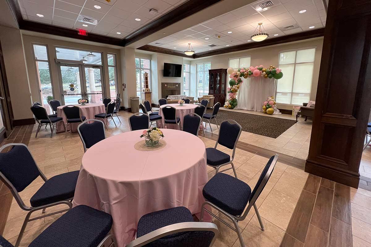 Tables set with pink tablecloths and balloon arch photo area