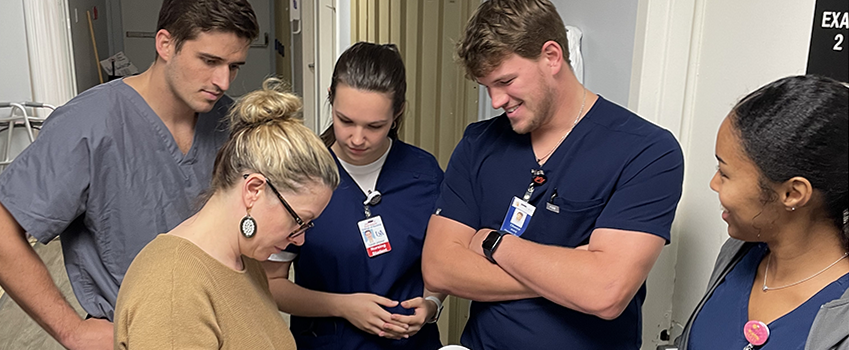 Medical, pharmacy, and nursing students are debriefing with the preceptor to discuss an treatment plan for the patient. 