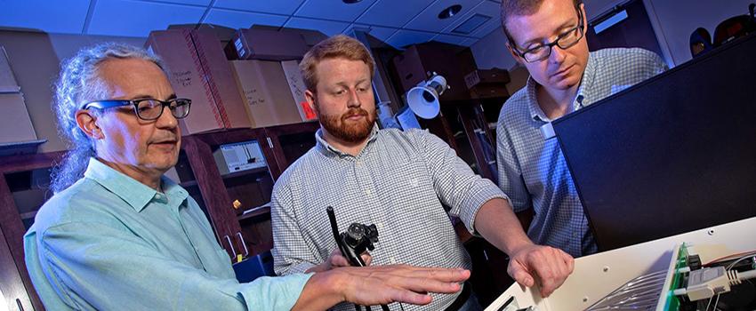 Thomas Rich, Ph.D., professor of pharmacology at the University of South Alabama College of Medicine (far left), and Silas Leavesley, Ph.D., associate professor of chemical and bimolecular engineering at USA (far right), work in an engineering lab with Craig Browning, a doctoral student in the science systems engineering program at USA.