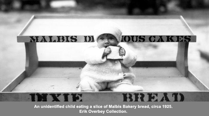 An unidentified child eating a slice of Malbis Bakery bread, circa 1925
