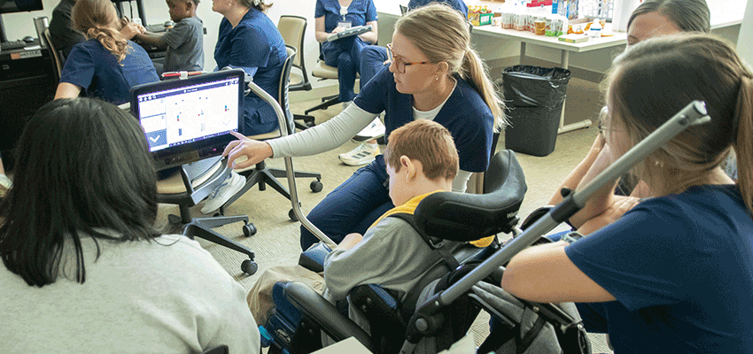 USA Allied Health students working with child at the Alabama Head Injury Foundation Camp looking at monitor.