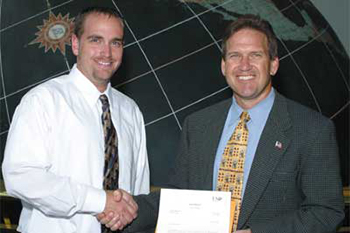 Michael Burnett (l) receives the 2004 ExxonMobil Junior Scholarship Award from Mike Leach (r), ExxonMobil Plant manager.
