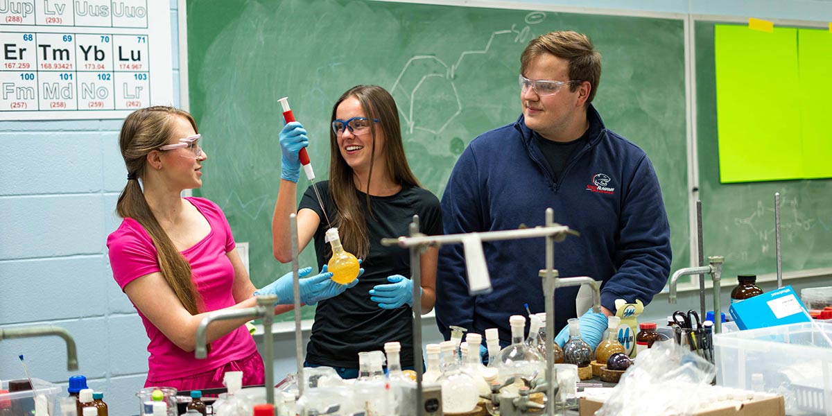 Three students working in Chemistry lab.