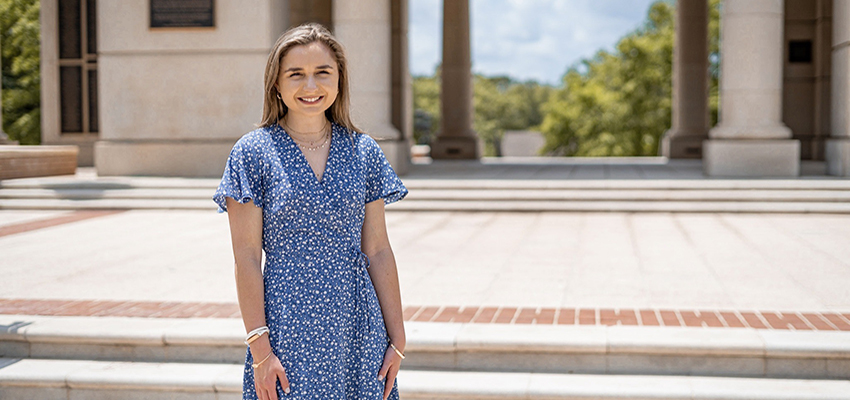 Hannah Giannini standing outside on steps in front of Moulton Tower.