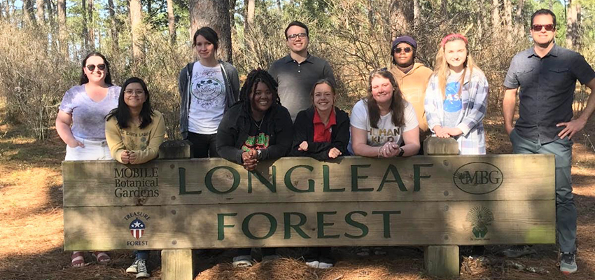 Students and professors standing behind the Longleaf Forest sign.