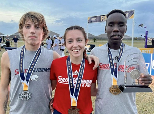 Adele Magaud stnading with two other teammates with race medals.