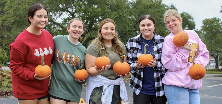 Five students holding pumpkins.