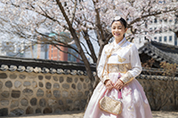 Woman in traditional Korean dress smiling outside.