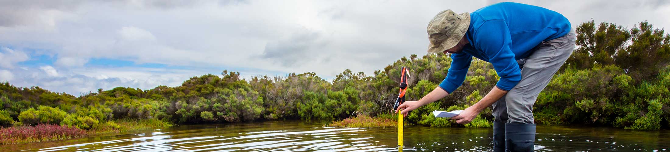 Man with measuring stick in water.