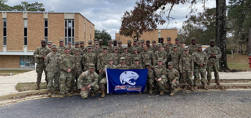 South Army ROTC Cadets standing outside holding up Jag flag.