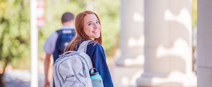 Student smiling looking over shoulder with backpack on.